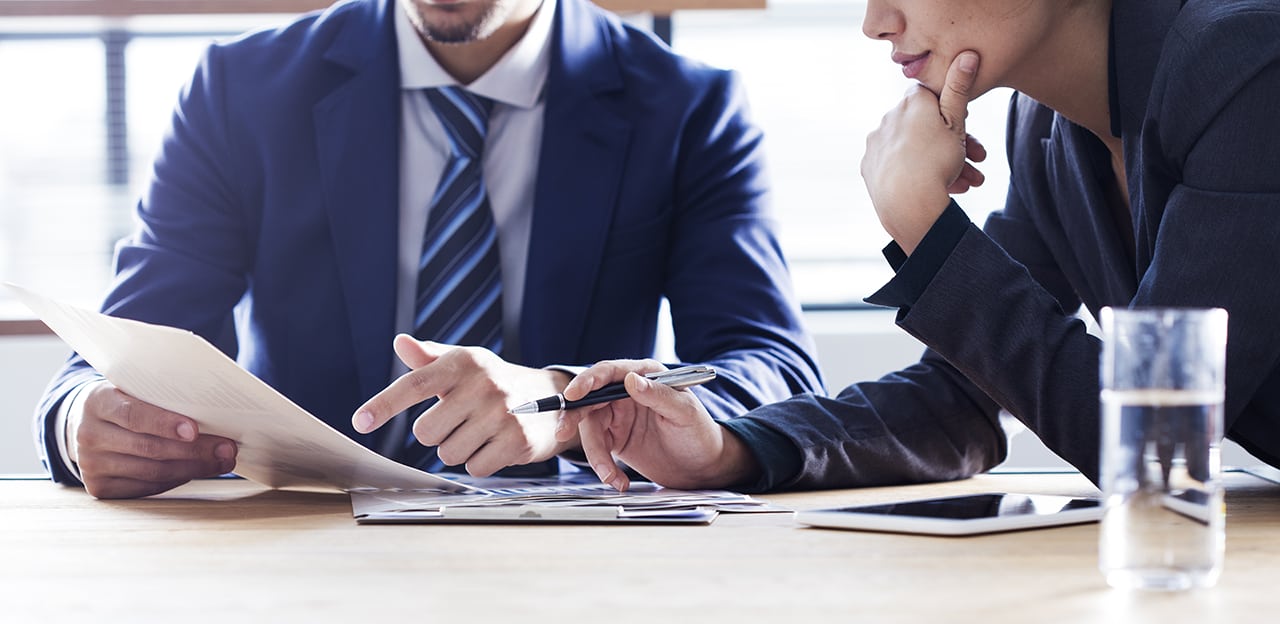 Businessman and businesswoman thoughtfully discussing documents at a table